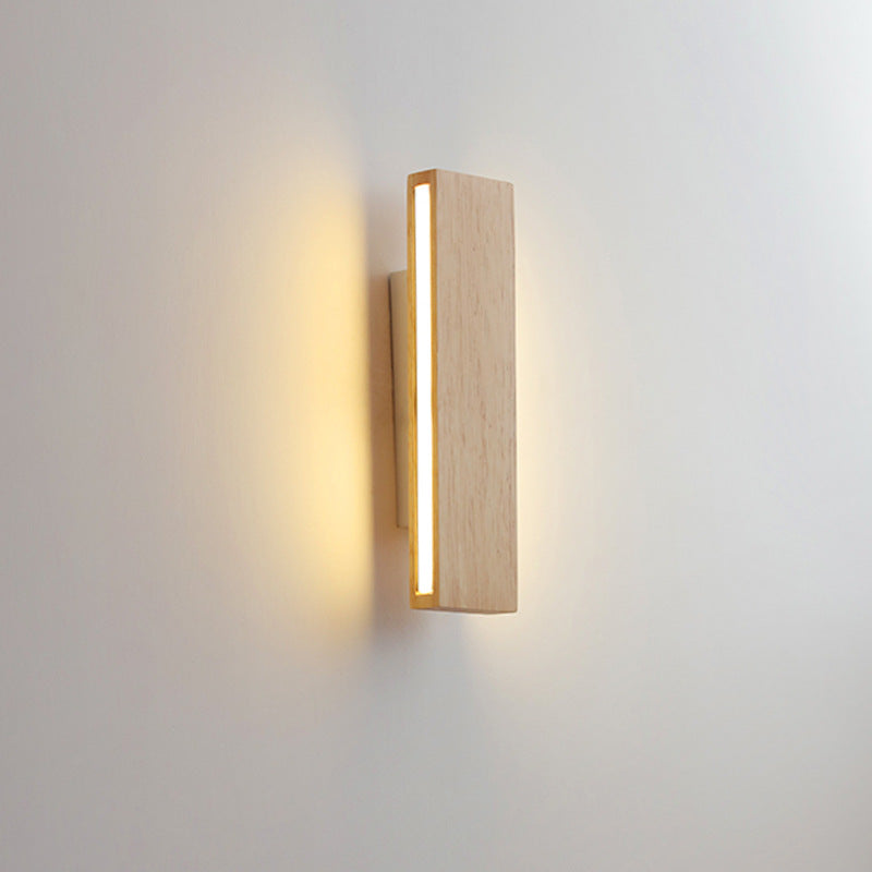 Vertical wooden wall lamp with a lit strip along its left edge, glowing warmly against a light wall. 10