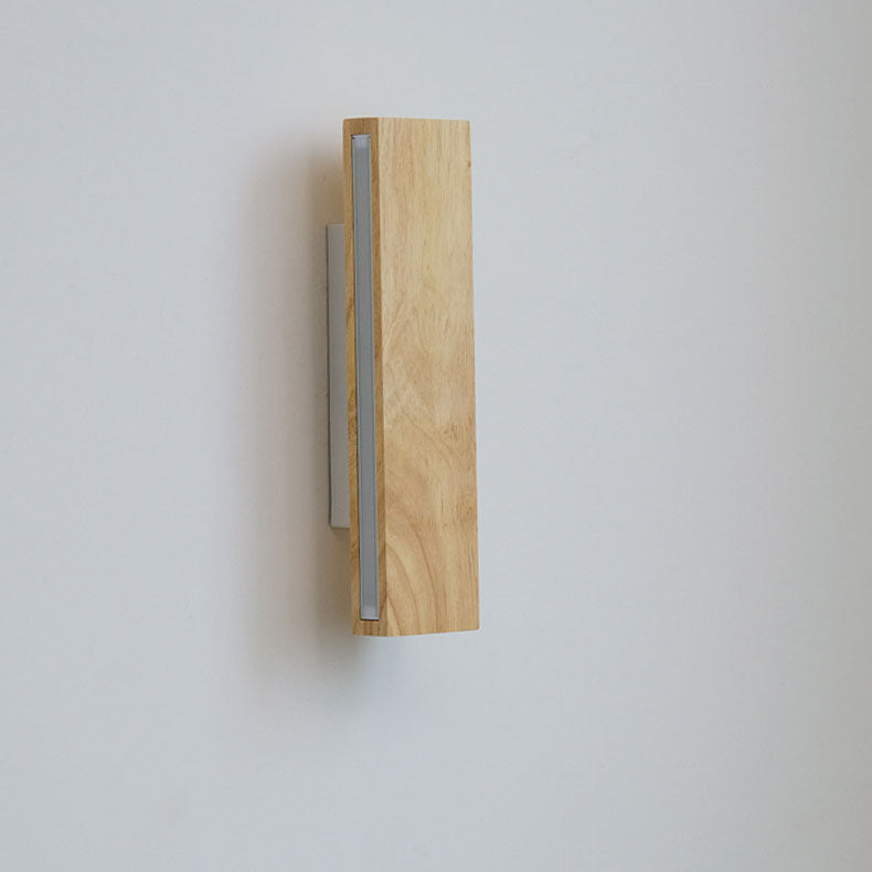 Unlit vertical wooden wall lamp seen from an angle, showing the grey diffuser strip and wood grain. 11