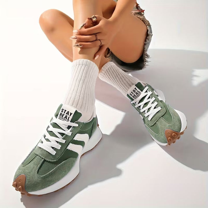 Zielone sneakersy z zamszu na stopach siedzącej modelki w białych skarpetkach i dżinsowych szortach 7