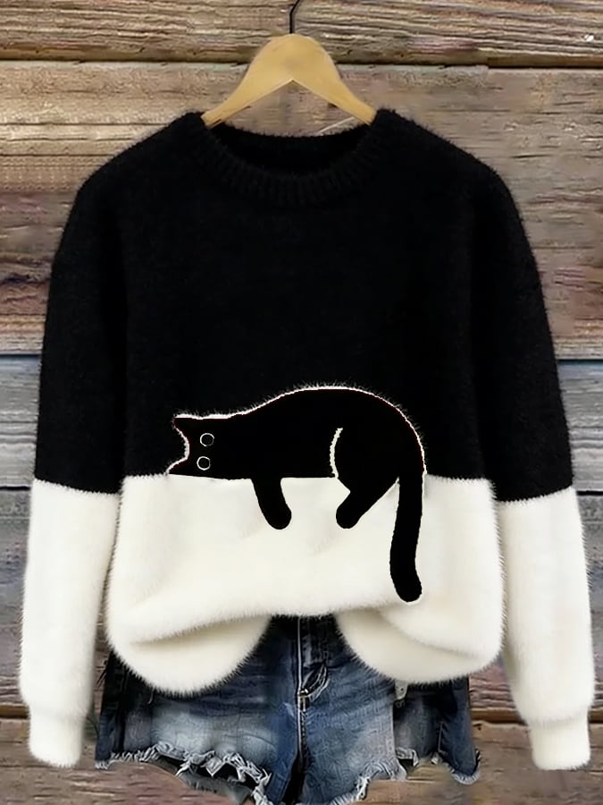Puszysty sweter w kolorze czarnym z białym dołem i czarnym kotem, na drewnianym wieszaku 5