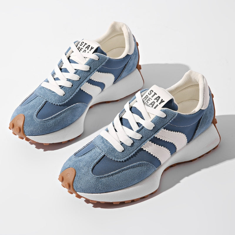 Niebieskie sneakersy z zamszowymi wstawkami i białymi paskami, sfotografowane parą z góry na jasnym tle 2