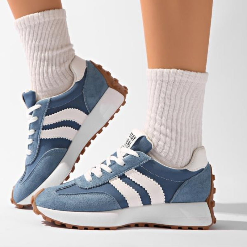 Niebieskie sneakersy z białymi paskami na nogach modelki w białych prążkowanych skarpetach, widok z boku 8