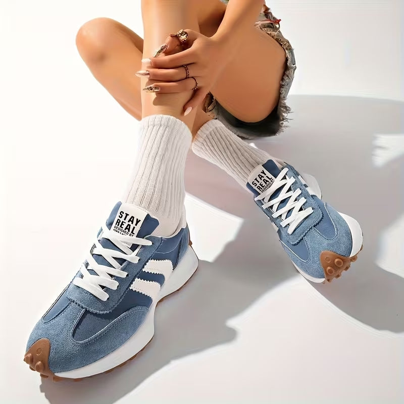Niebieskie zamszowe sneakersy na stopach siedzącej modelki w białych skarpetkach i dżinsowych szortach 9