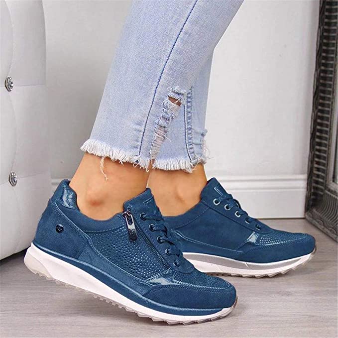 Niebieskie sneakersy z bocznym zamkiem i ozdobnymi cyrkoniami na przodzie, założone do rozerwanych dżinsów, widok z boku. 3