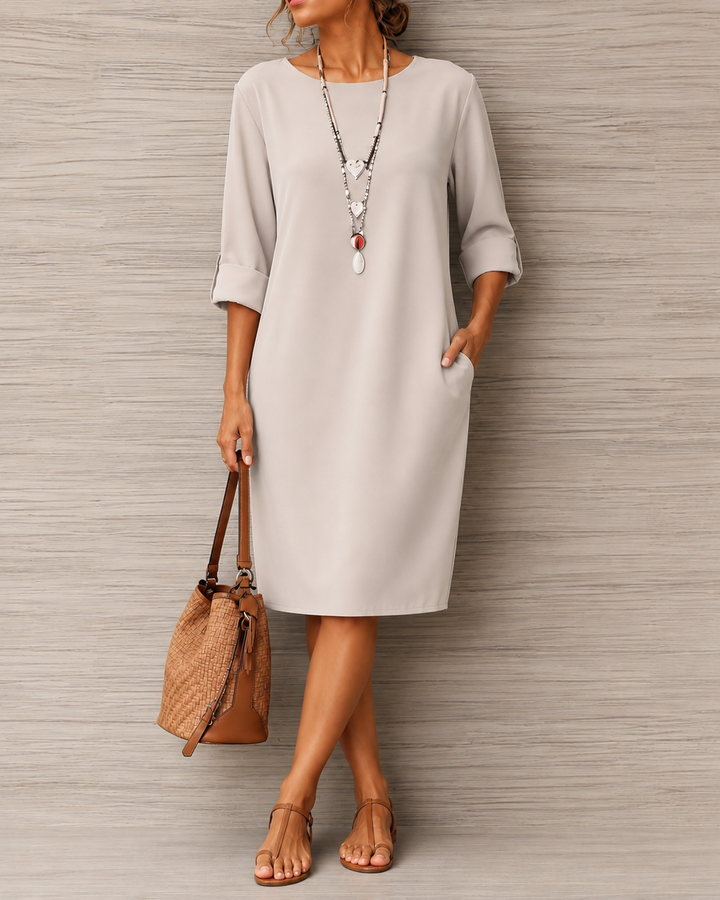 Jasnoszara sukienka z kieszeniami i podwijanymi rękawami na modelce, z plecioną torbą i sandałami 8