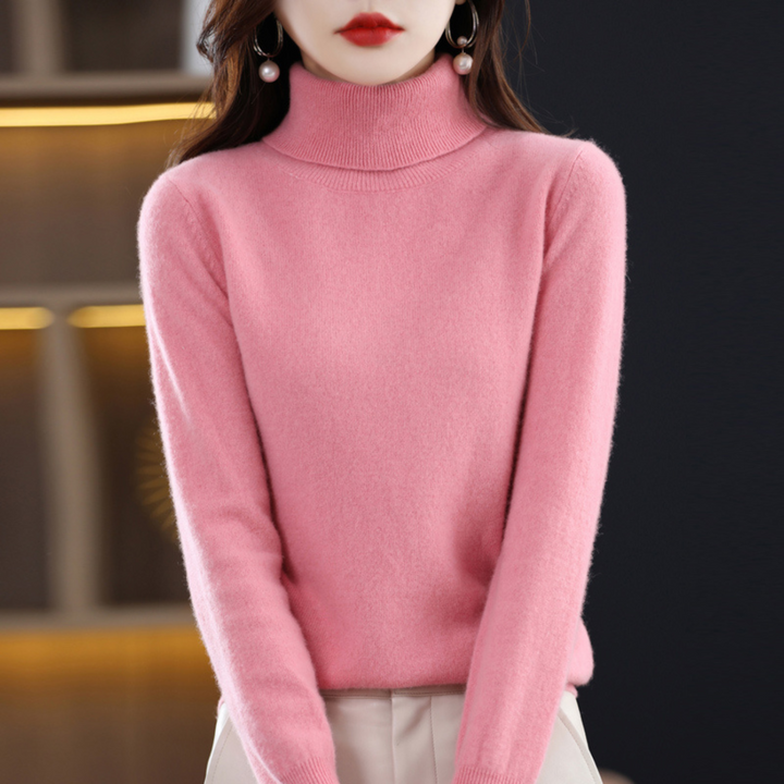 Różowy sweter z golfem na stojącej modelce, zestawiony z jasnymi spodniami. 7