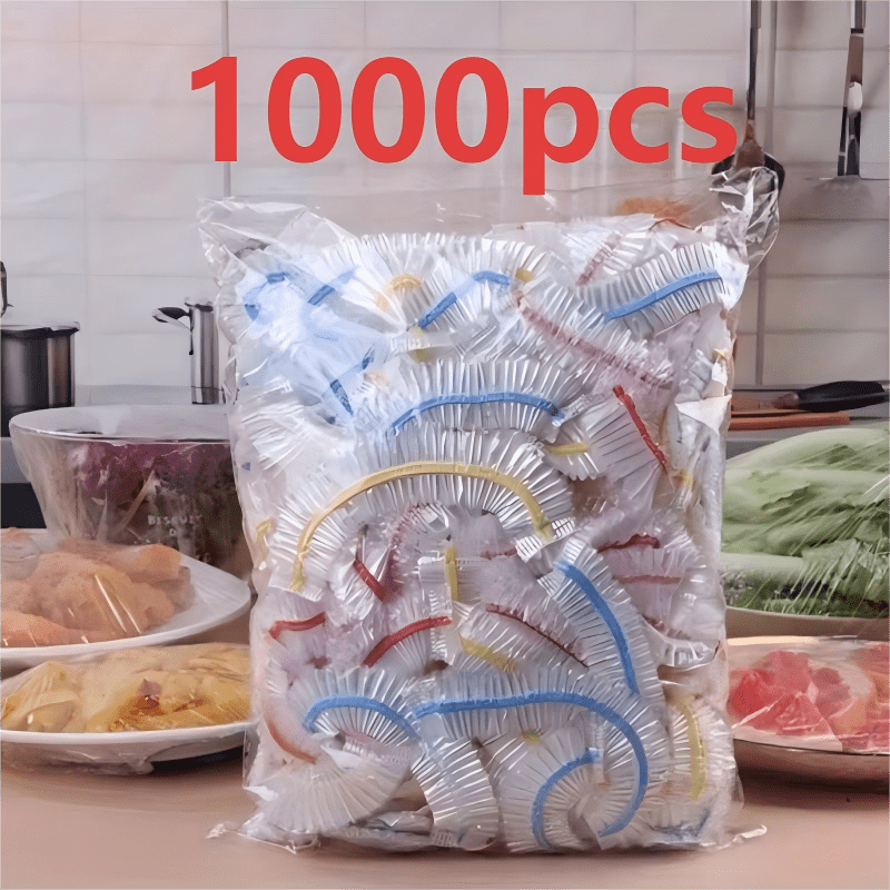 Torba z kolorowymi pokrywkami na blacie kuchennym, w tle talerze z mięsem, makaronem i warzywami przykryte folią. 3