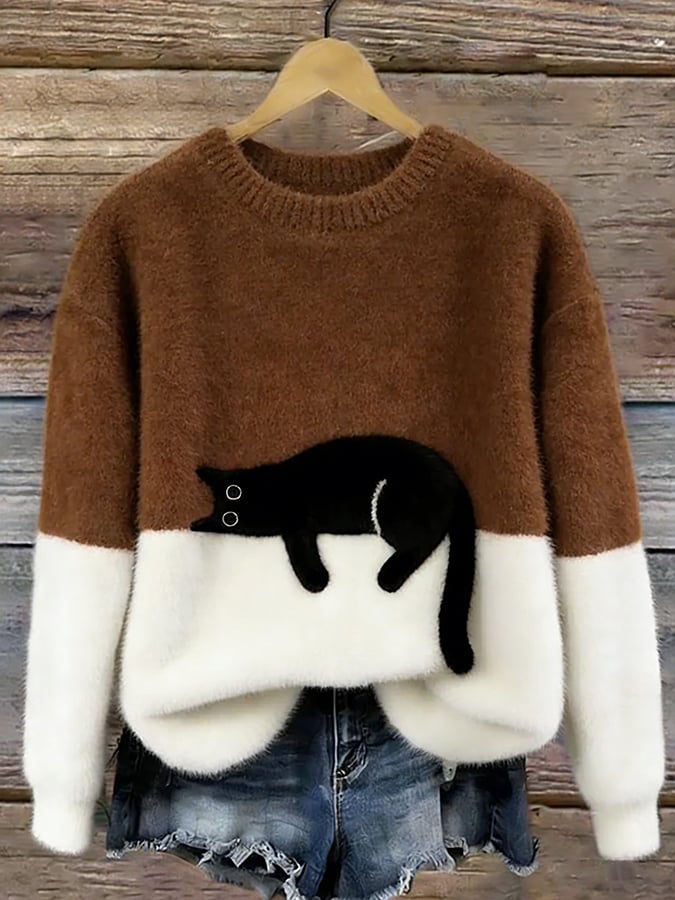 Puszysty sweter w kolorze brązowym z białym dołem i czarnym kotem, na drewnianym wieszaku 9