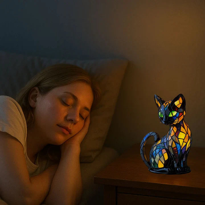 Świecący witrażowy kot na nocnej szafce, obok śpiąca kobieta w przyćmionej sypialni 3