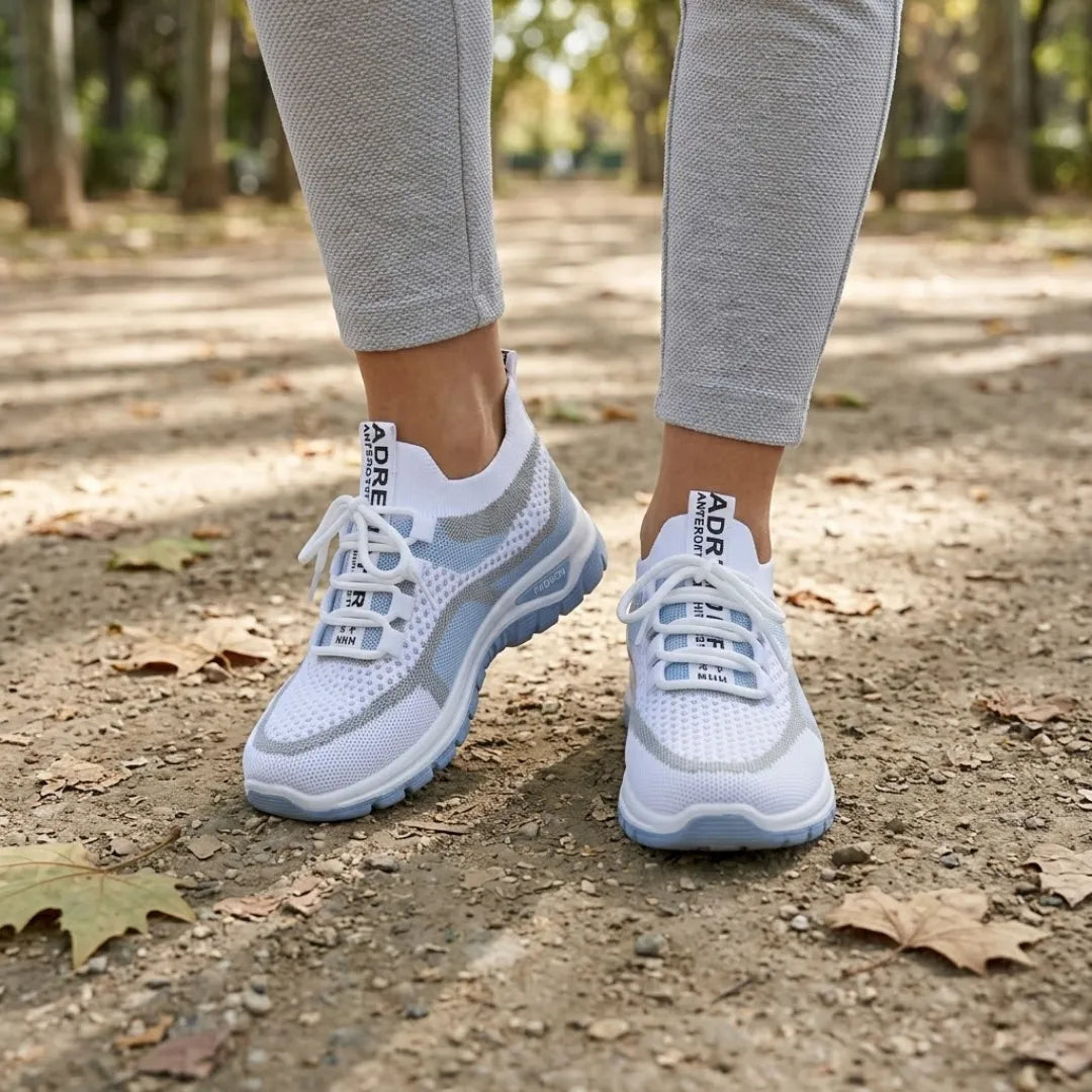 Białe sneakersy z niebieską podeszwą noszone na stopach, spacer ścieżką w parku wśród jesiennych liści. 2