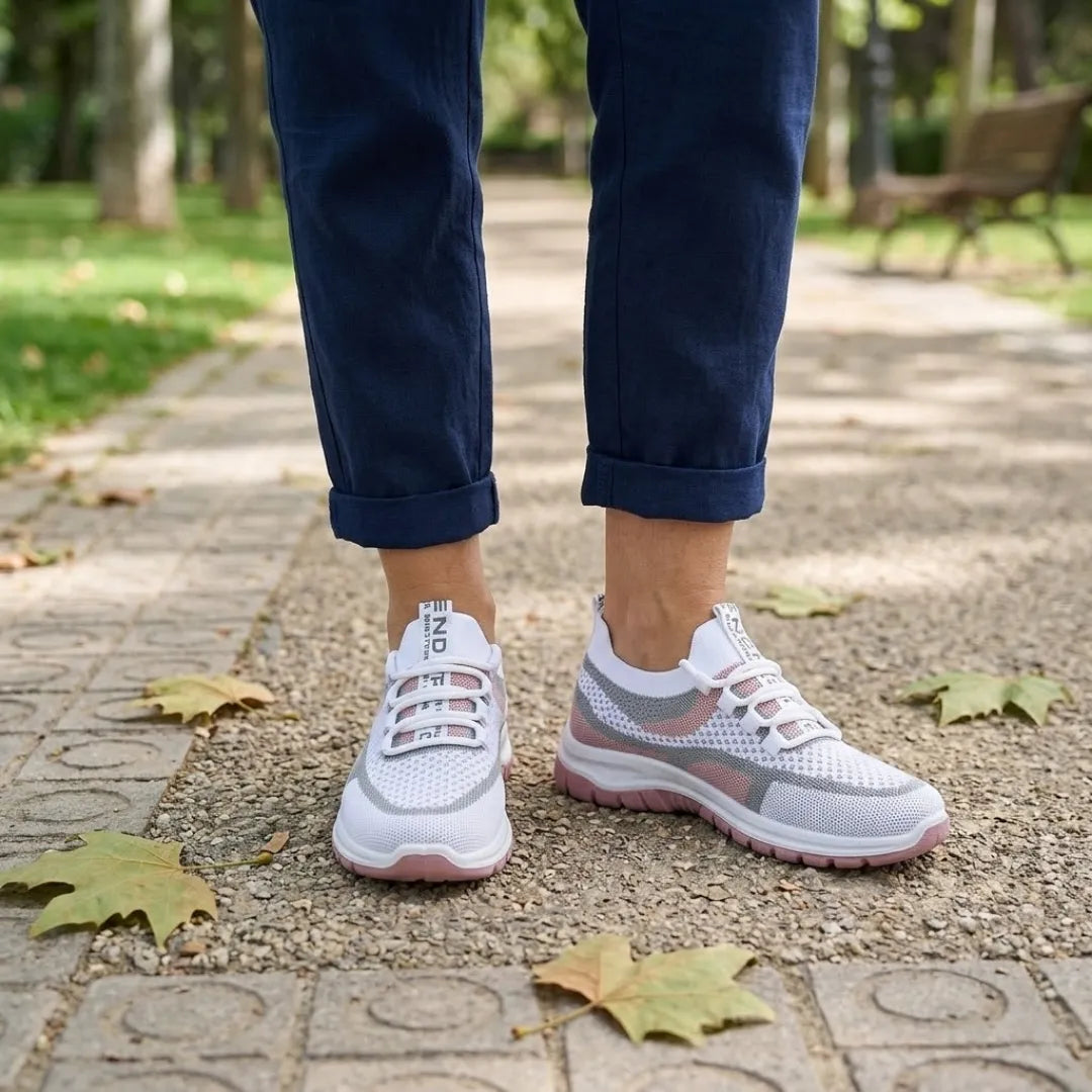 Białe sneakersy z różową podeszwą noszone z granatowymi spodniami podwiniętymi do kostek, na parkowej alejce. 20