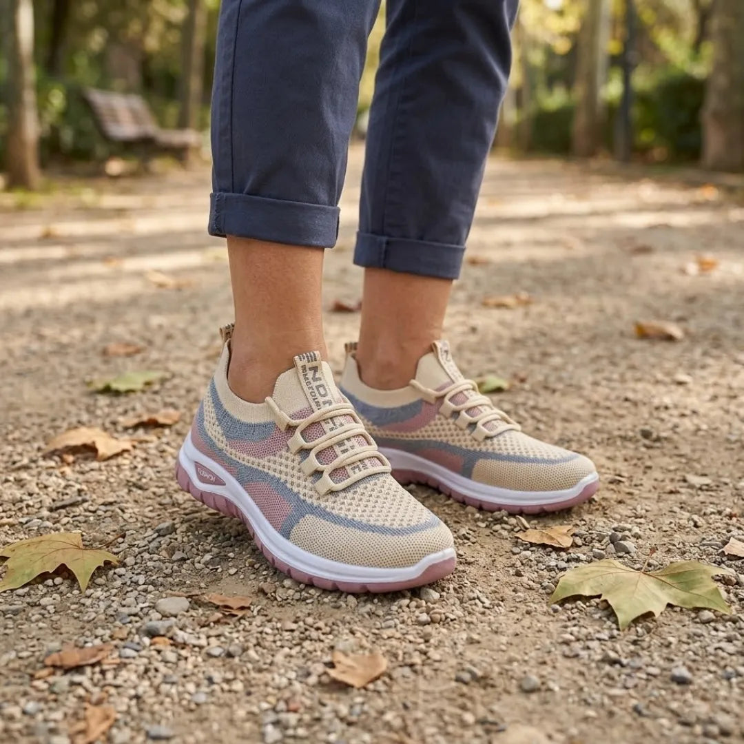 Kobiece stopy w beżowych sneakersach z różowymi i niebieskimi wstawkami na parkowej alejce wśród jesiennych liści. 29