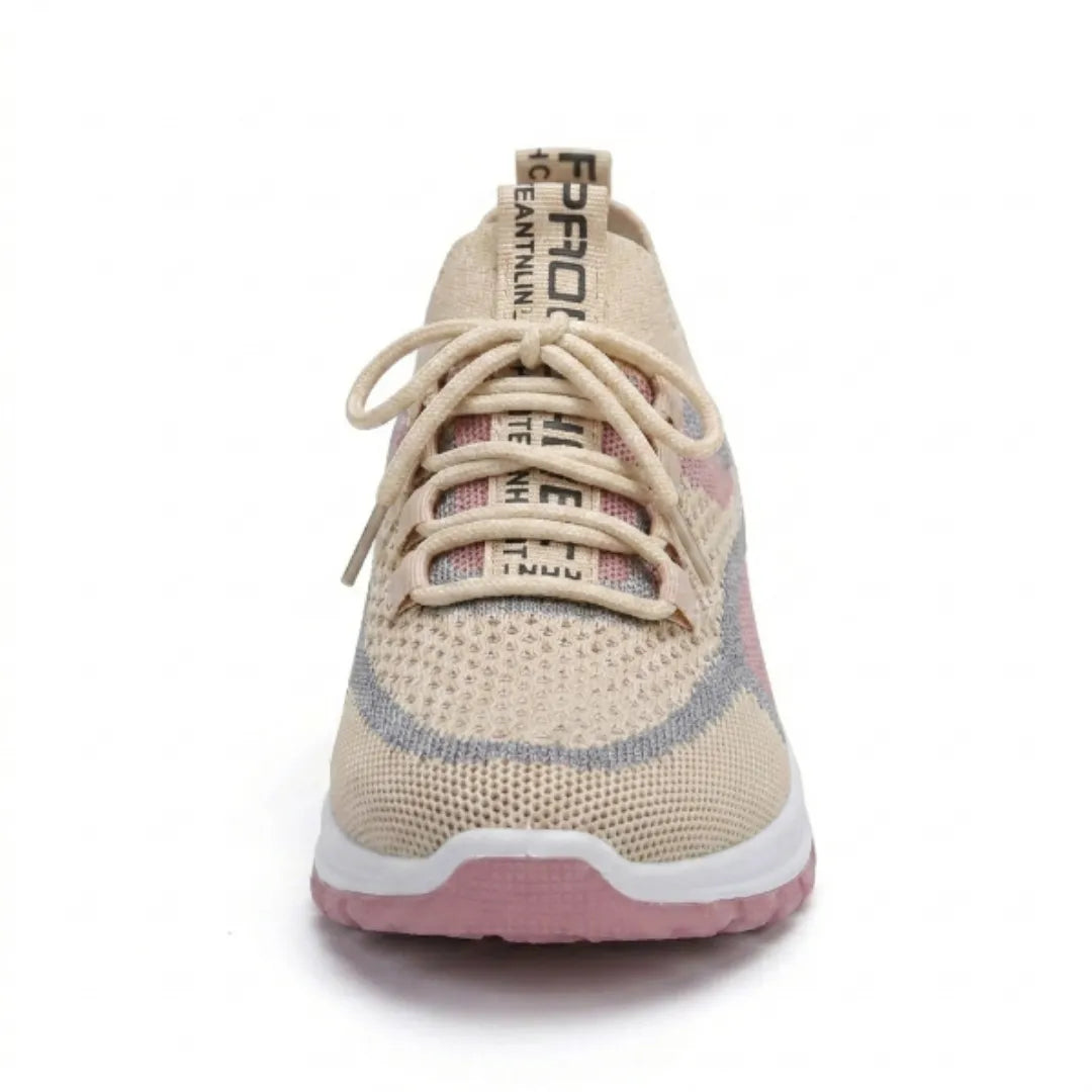 Beżowy sneaker z siateczki widziany od przodu: sznurowanie, różowo-szare wstawki, szeroki nosek i różowa podeszwa. 35