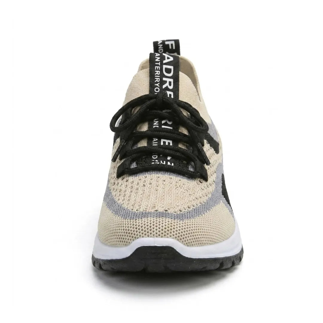 Sneaker widziany od przodu: beżowa dziurkowana dzianina, czarne sznurowanie, szare i czarne pasy, uchwyt na pięcie oraz biała podeszwa z czarnym spodem. 44