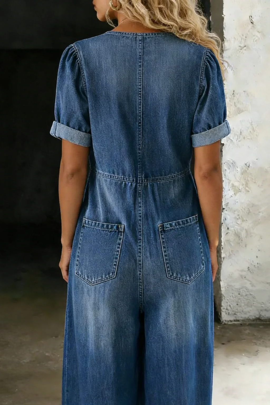 Tył granatowego kombinezonu z denimu na modelce: dwie kieszenie, podwinięte krótkie rękawy i marszczona talia 5