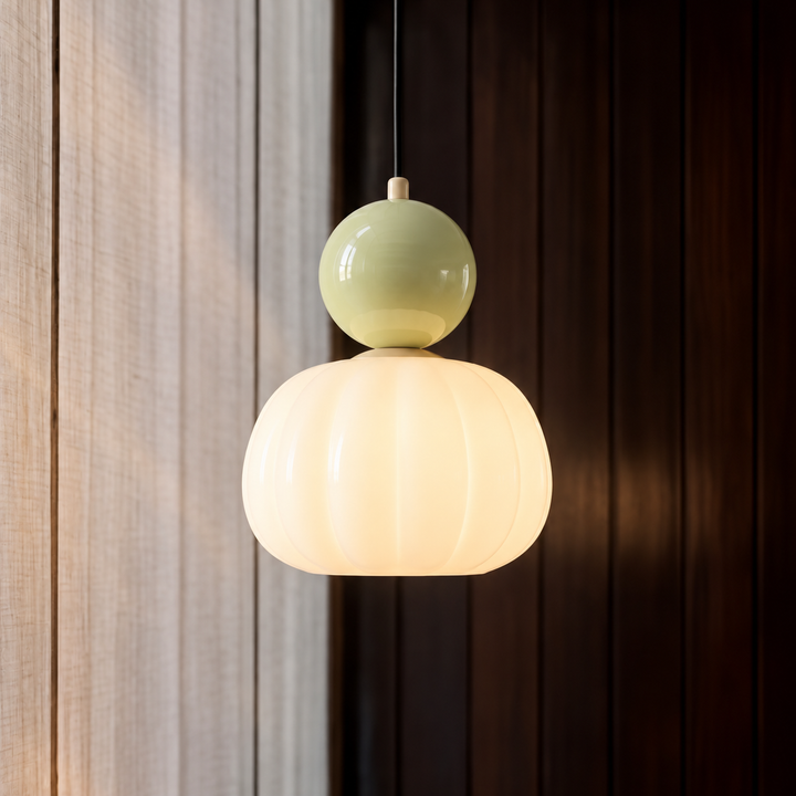 Pojedyncza lampa z jasnozieloną kulą nad świecącym ryflowanym kloszem, na tle jasnego i ciemnego drewna 2