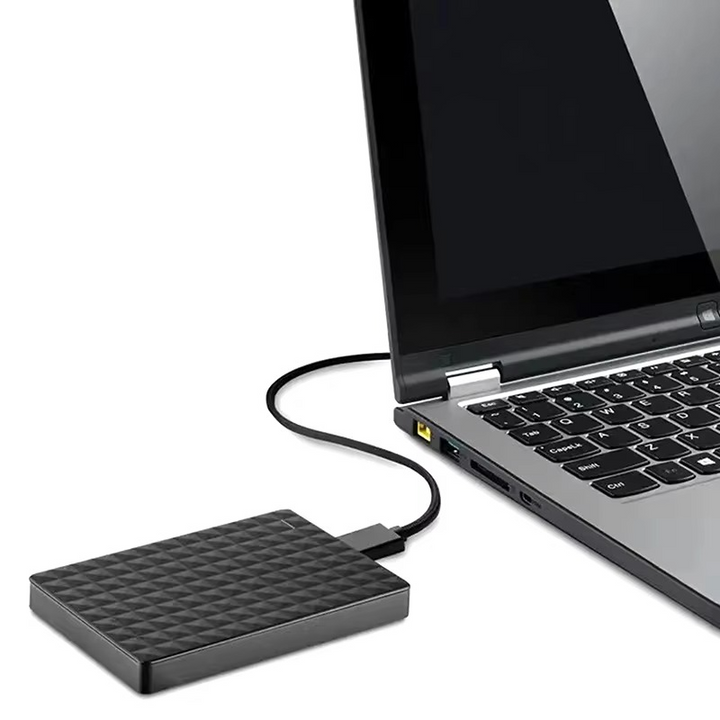 Dysk obok otwartego laptopa, podłączony kablem do portu USB w boku komputera 5