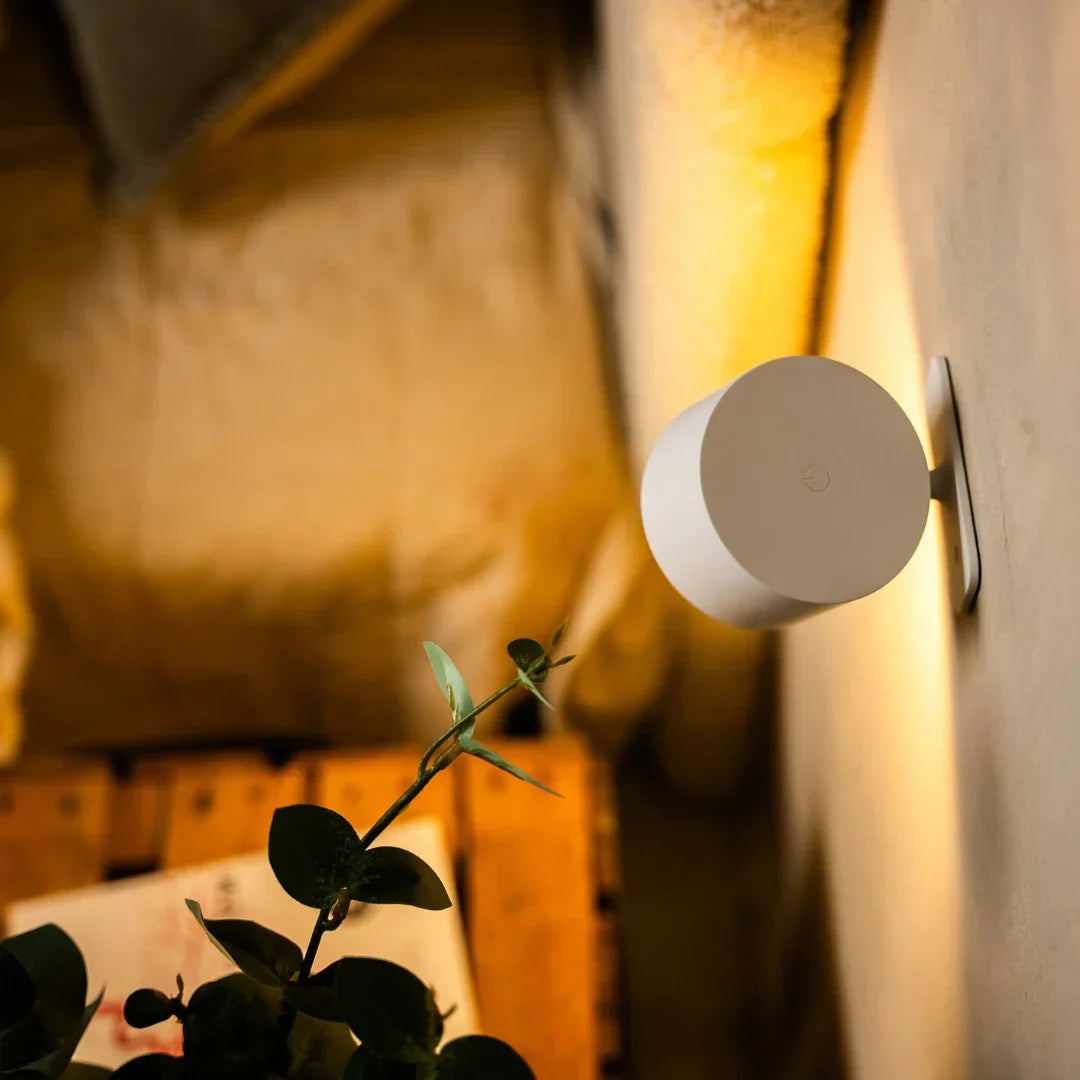 Biała lampa widziana od tyłu z przyciskiem dotykowym, na ścianie obok gałązki eukaliptusa 4