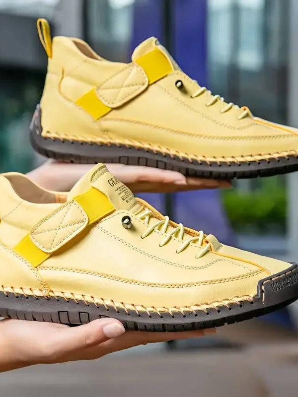 Żółte sneakersy z żółtym paskiem elastycznym i ciemną podeszwą, trzymane na dłoniach 15