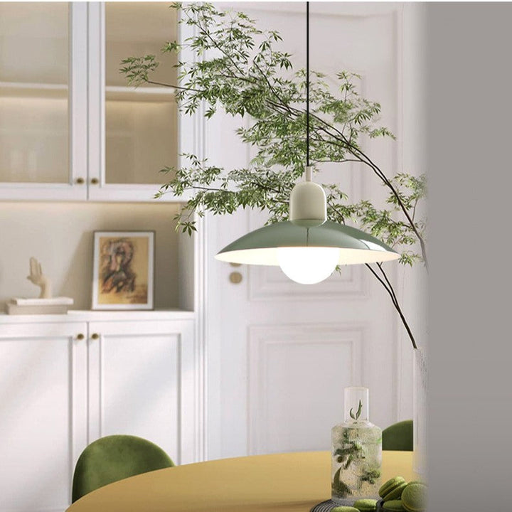 Zielona lampa wisząca z kremowym uchwytem i szklaną kulą w białej jadalni z gałęziami 7