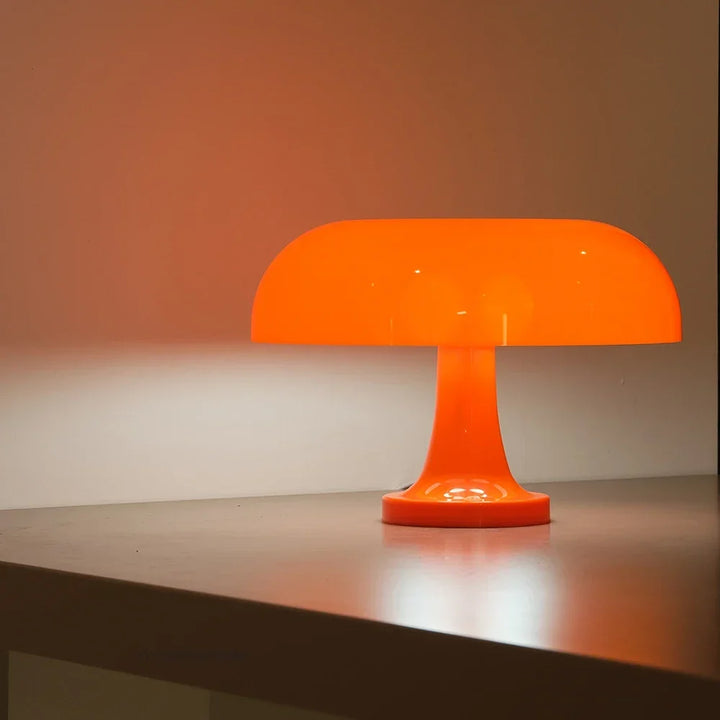 Pomaraรฑczowa lampa grzybek ลwieci na brzegu blatu, rzucajฤ…c ciepลe pomaraรฑczowe ลwiatลo na ลcianฤ™ za niฤ…. 6
