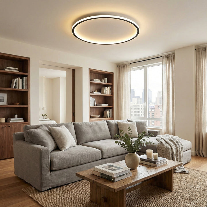 Okrągła lampa LED zawieszona nad szarą sofą, drewnianym stolikiem i regałami w jasnym salonie. 4