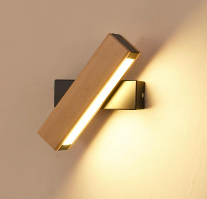 Close-up of the lit wooden lamp bar rotated at an angle on a black wall mount, casting warm light. 7