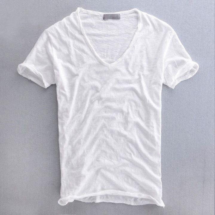 Biała koszulka z dekoltem w serek i podwiniętymi rękawami, rozłożona płasko na szarym tle, widok z przodu. 2