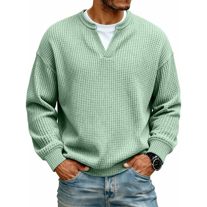 Sweter w odcieniu jasnej zieleni noszony przez modela z rękami w kieszeniach jeansów, ujęcie z przodu. 4