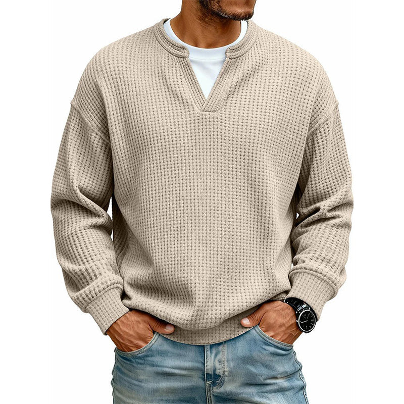 Beżowy sweter waflowy z wycięciem przy dekolcie na modelu, z białą koszulką pod spodem i jeansami. 5