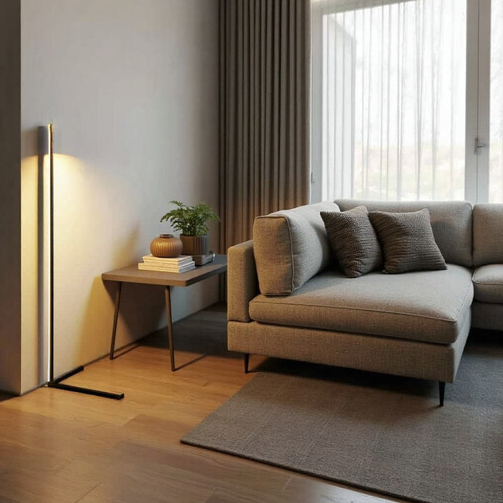 Lampa z ciepłym światłem przy ścianie w salonie, obok bocznego stolika z roślinką i szarej narożnej sofy 6