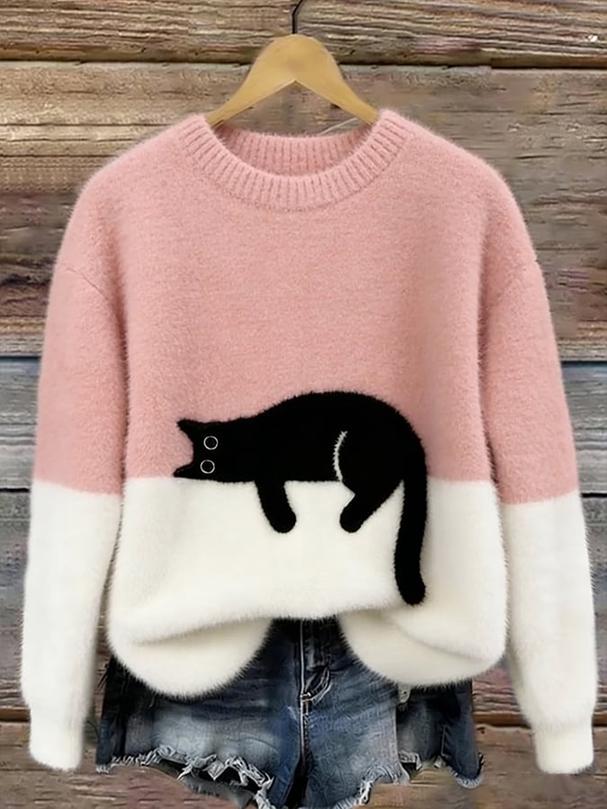 Puszysty sweter w kolorze jasnoróżowym z białym dołem i czarnym kotem, na drewnianym wieszaku 2
