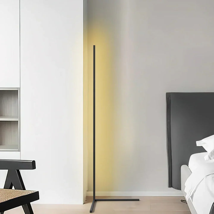Czarna lampa z żółtawą poświatą w jasnym wnętrzu, obok drewnianego krzesła i fragmentu łóżka 7