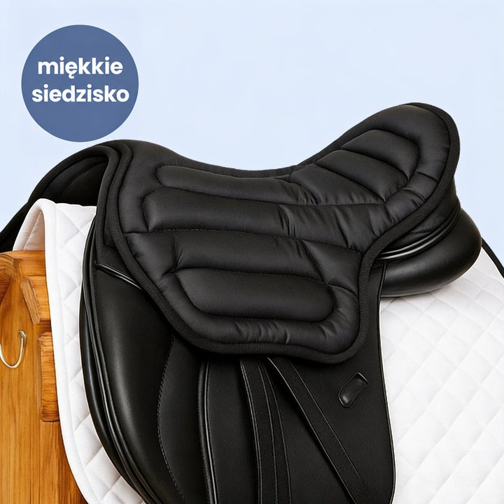 Czarna pikowana nakładka na siodło ujeżdżeniowe, położona na białym czapraku w stajni 1