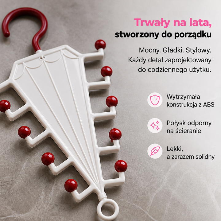 Biały wieszak z czerwonym haczykiem i czerwonymi kulkami na jasnym kamiennym blacie, widok z góry 3
