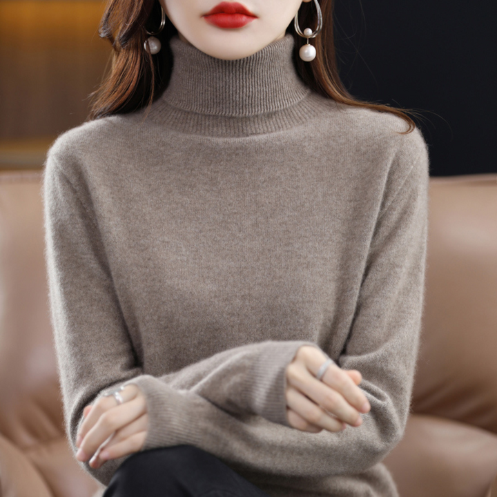 Sweter z golfem w kolorze szarobrązowym na modelce siedzącej na kanapie, widoczny prążkowany kołnierz i mankiety. 13