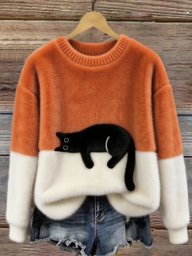 Puszysty sweter w kolorze pomarańczowym z białym dołem i czarnym kotem, na drewnianym wieszaku 3