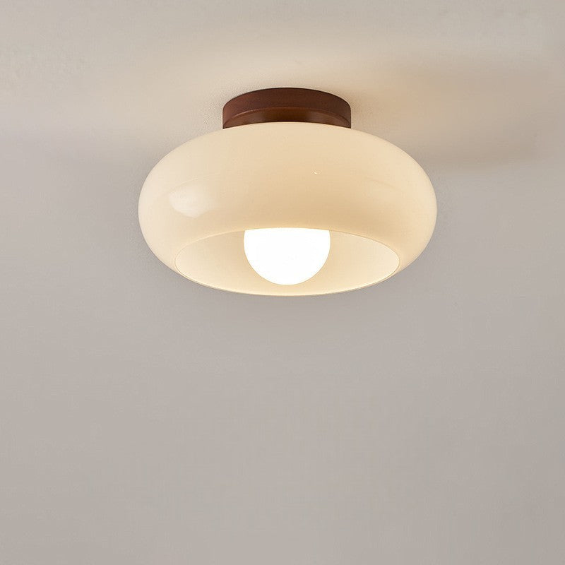Lampa sufitowa z kremowym szklanym kloszem, matową żarówką i brązową drewnianą podsufitką na jasnym tle 6