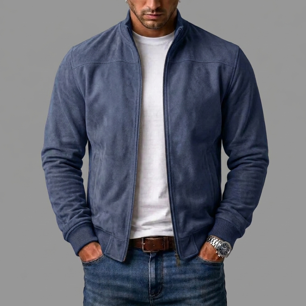Mężczyzna w granatowej kurtce bomber ze ściągaczami, rozpiętej na białym t-shircie, w jeansach i z zegarkiem na nadgarstku. 5