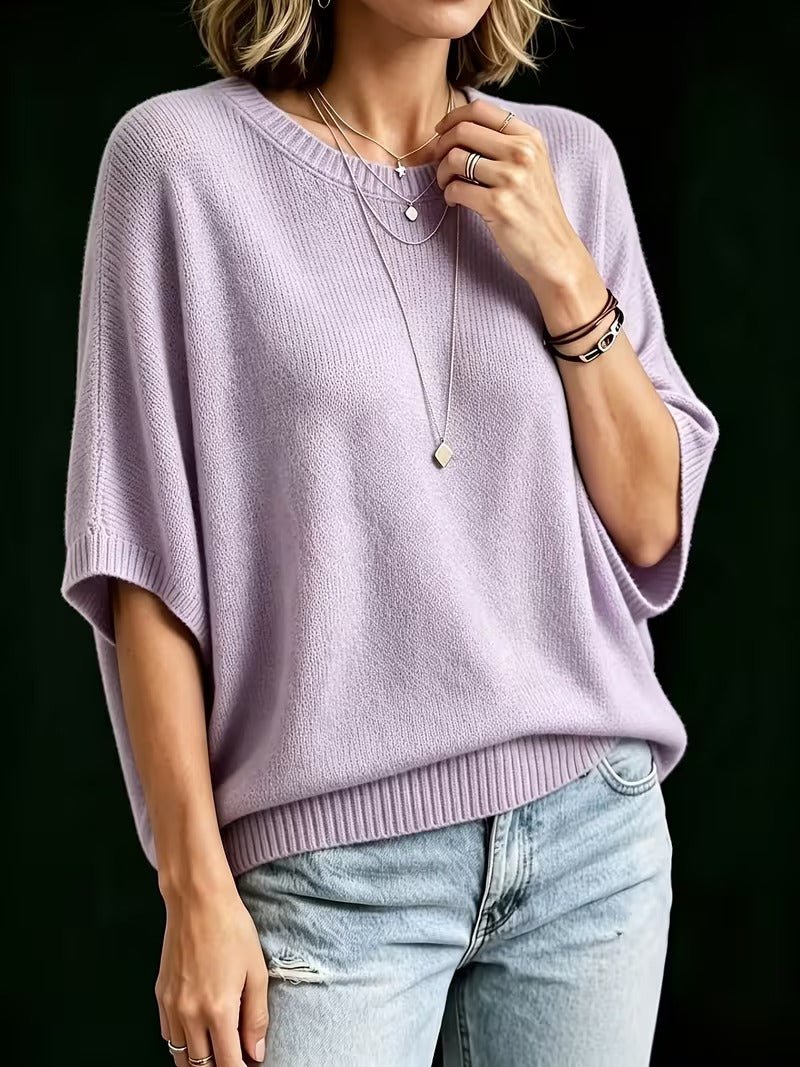 Liliowy top z dzianiny pod kątem, modelka dotyka naszyjnika, rękaw batwing i ściągacz na dole. 8