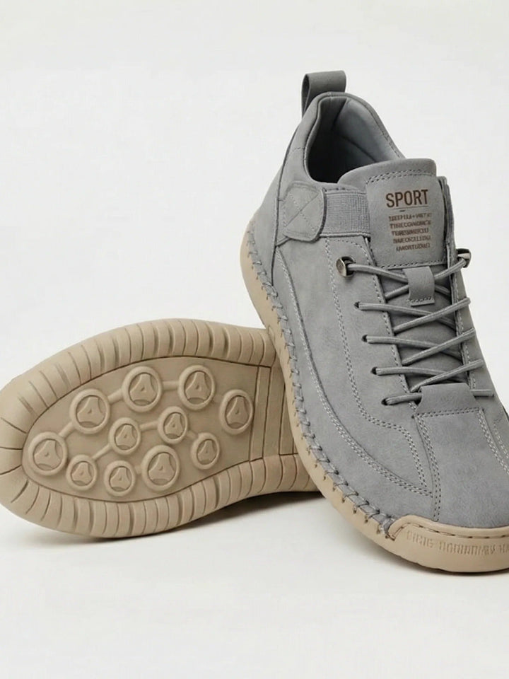 Szare zamszowe sneakersy z beżową podeszwą o wzorze w kółka, jeden but oparty na drugim 17