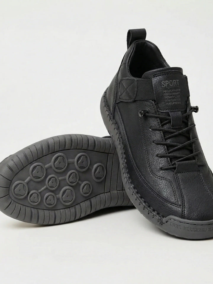 Czarne sneakersy ze skóropodobnej cholewki i szarą podeszwą z wzorem, jeden but oparty na drugim 1