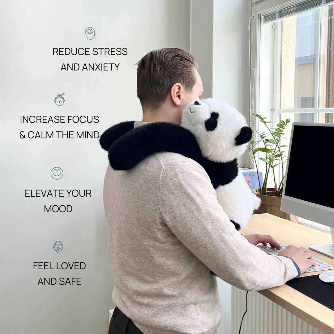 Mężczyzna pracuje przy biurku w stójce, a pluszowa panda obejmuje długimi ramionami jego szyję i ramiona; obok napisy o redukcji stresu. 2
