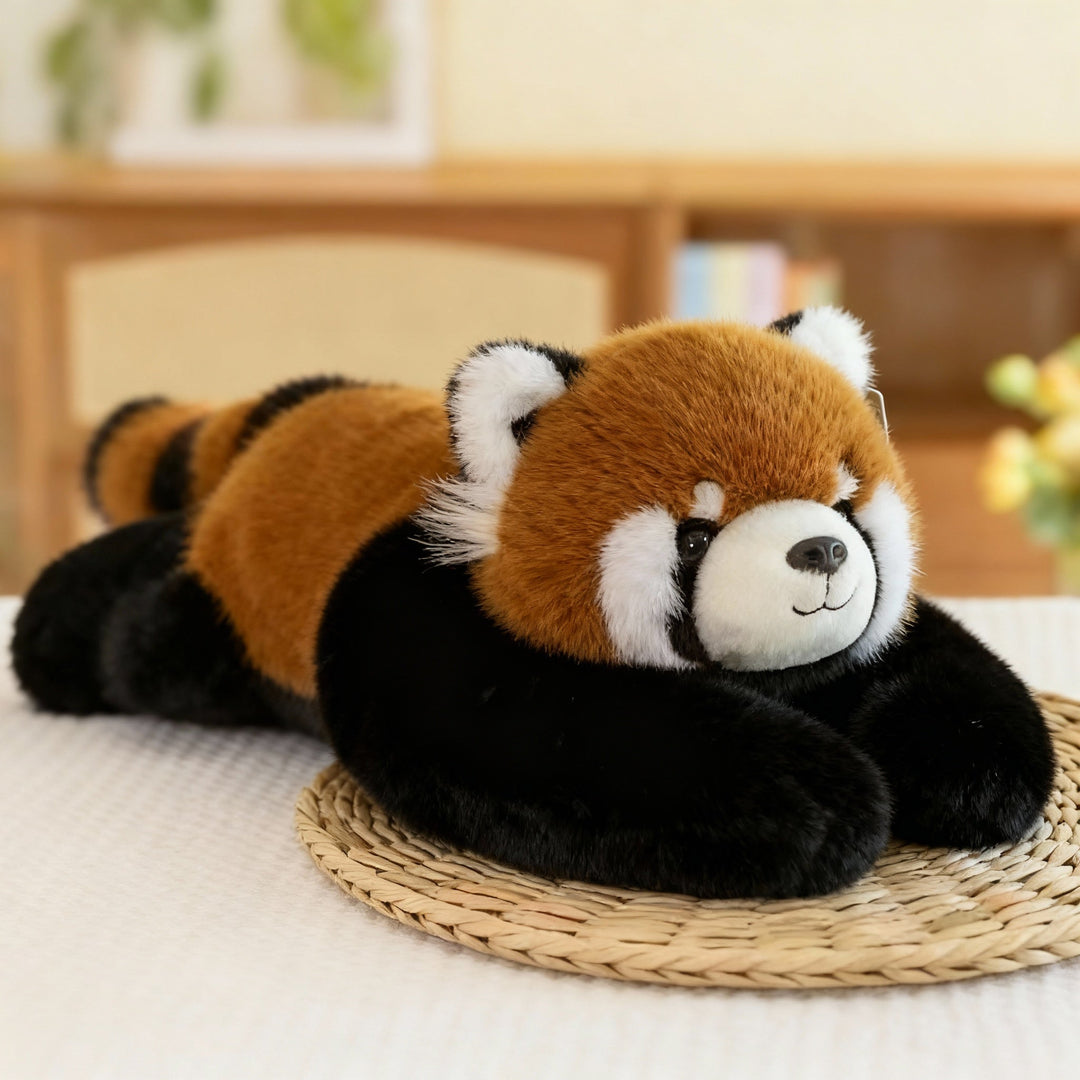 Pluszowa czerwona panda z rudym grzbietem, prążkowanym ogonem i czarnymi długimi ramionami leży na słomianej podkładce. 13