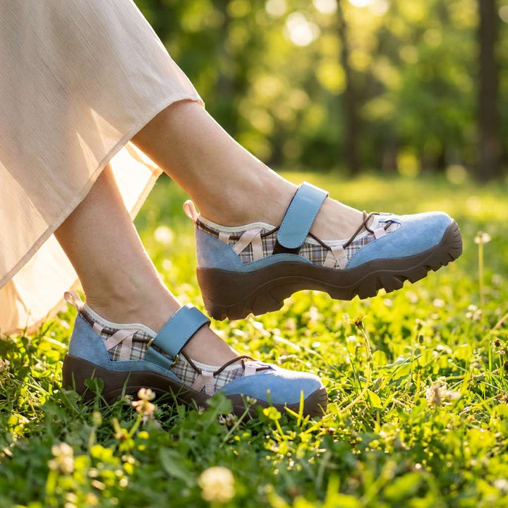 Niebieskie buty w kratkowane wstawki z paskiem na rzep, noszone z lekką spódnicą na trawie w słonecznym parku. 8