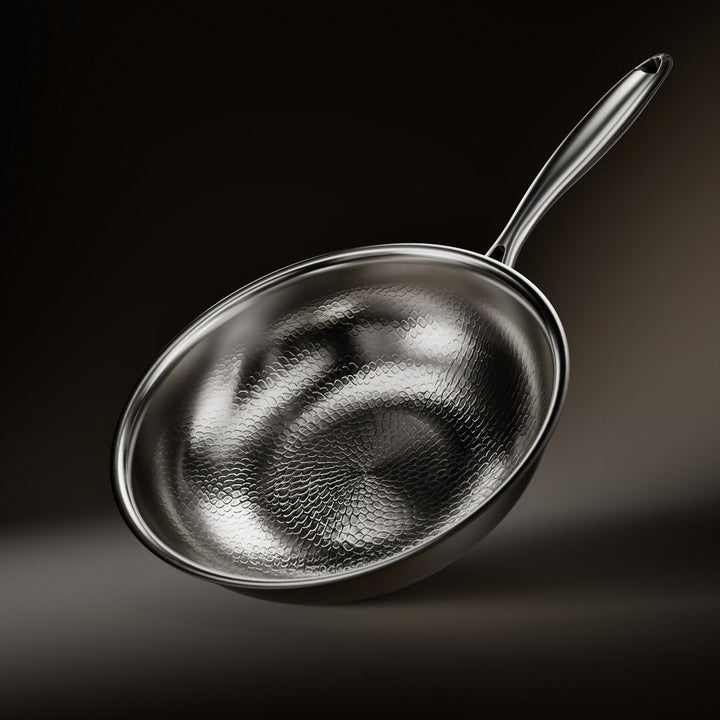 Wok widziany z góry pod kątem, ze wzorem ręcznie kutej łuski wewnątrz i metalowym uchwytem, na ciemnym tle. 1