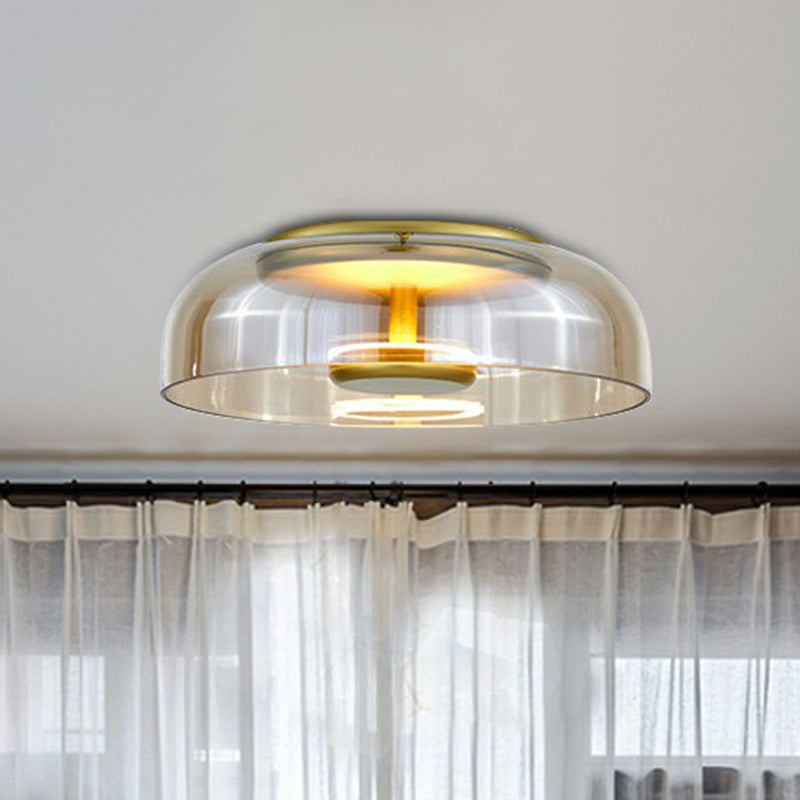 Lampa sufitowa z bursztynowym szklanym kloszem i złotą oprawą nad firanką w jasnym wnętrzu 2
