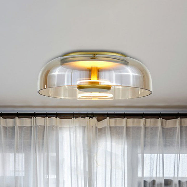 Lampa sufitowa z bursztynowym szklanym kloszem i złotą oprawą nad firanką w jasnym wnętrzu 2