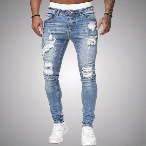 Mężczyzna w jasnoniebieskich jeansach slim z postrzępionymi dziurami na udach i kolanach, z białymi butami, widok z przodu. 2